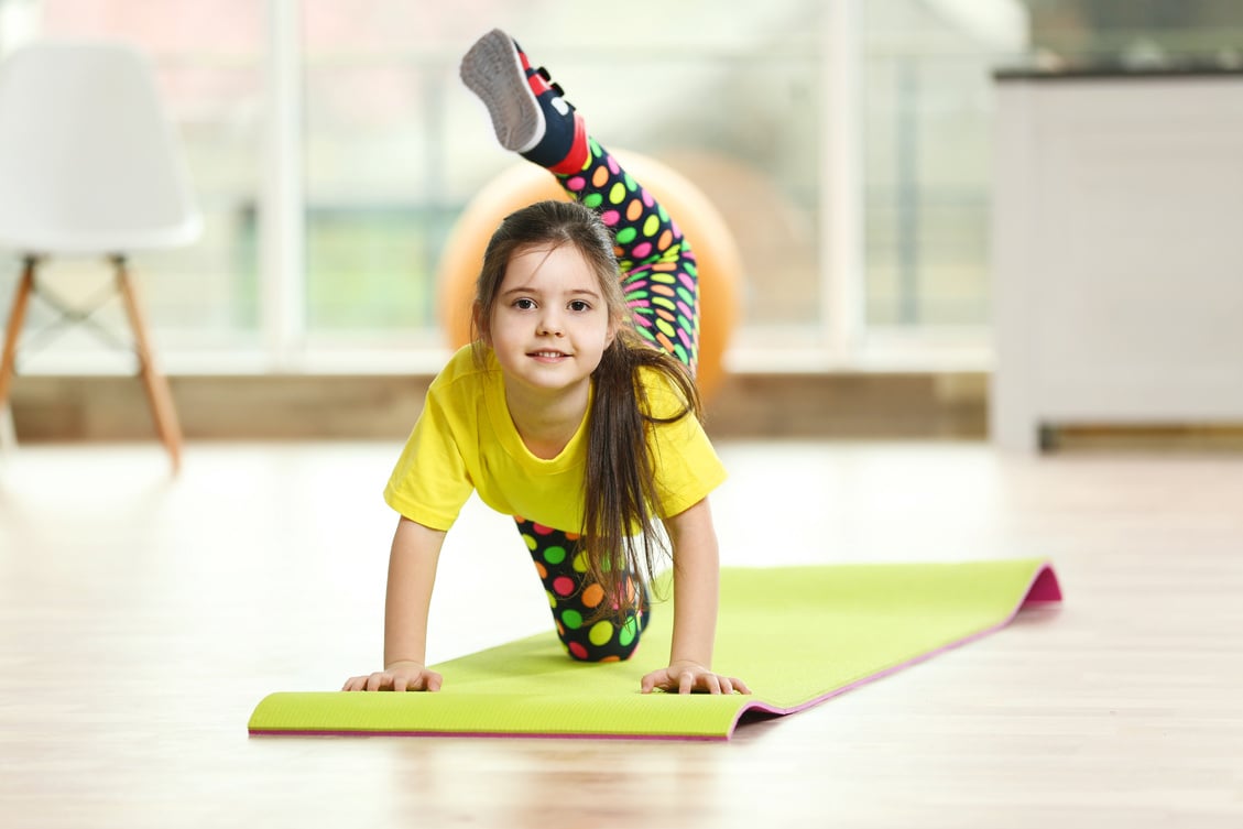 Little Cute Girl Practicing Yoga Pose on a Mat Indoor